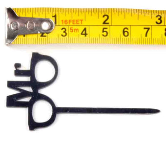 Black Mr cake topper with a measuring tape for scale on a white background