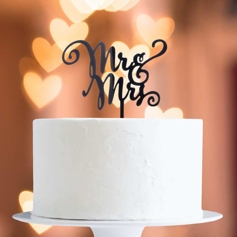 White cake with 'Mr & Mrs' topper against a blurred heart-shaped light background