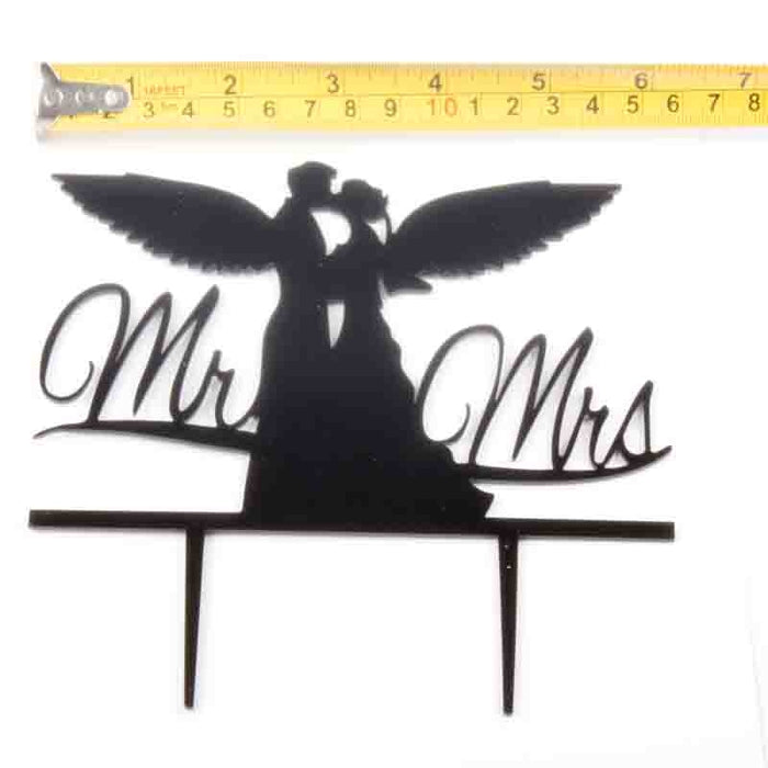 Decorative cake topper with 'Mr' and 'Mrs' text, featuring a couple with wings, on a white background.