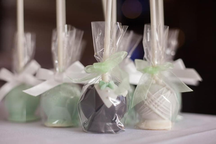 Decorative cake pops wrapped in clear cellophane with ribbons on a blurred background