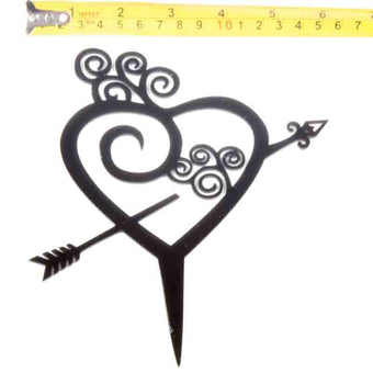 Cake topper heart with arrow on a white background, measured with a tape measure.