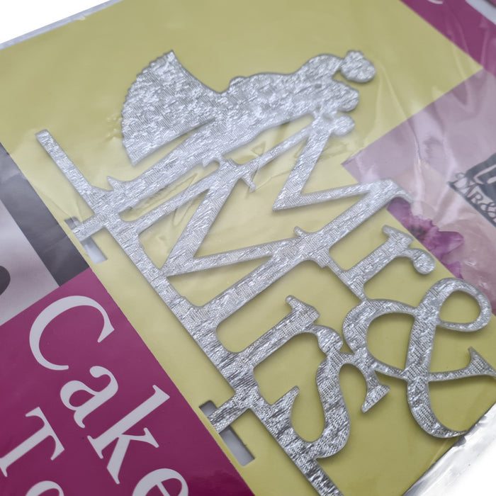 Silver cake topper with 'Mr' and 'Mrs' on a colourful background in packaging