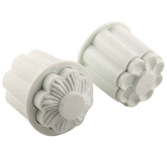 Two white plastic flower-shaped cookie cutters on a white background