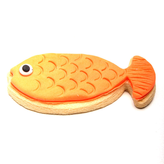 Fish-shaped cookie with orange body and black eye on a white background