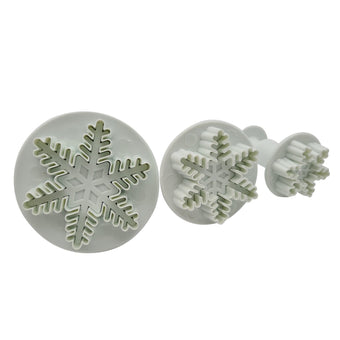 Set of three snowflake shaped fondant cutters on a white background