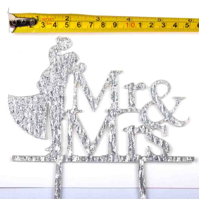 Decorative cake topper with 'Mr & Mrs' text and a measuring tape for scale.