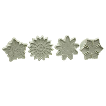 Four white flower-shaped fondant veiners on a white background
