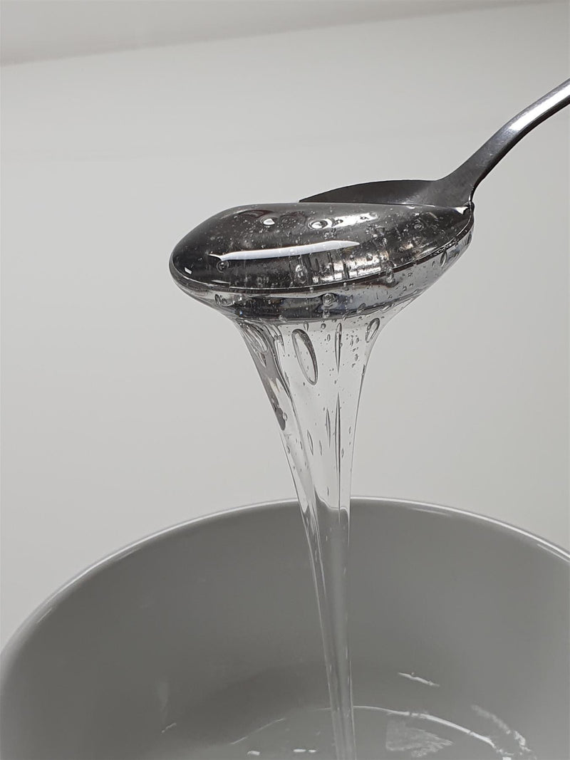Spoon pouring Glucose into a container with a white background