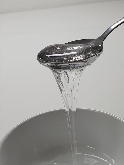 Spoon pouring Glucose into a container with a white background