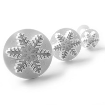 Set of three snowflake shaped fondant cutters on a white background