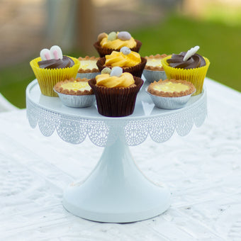 Assorted small desserts on a decorative cake stand outdoors.