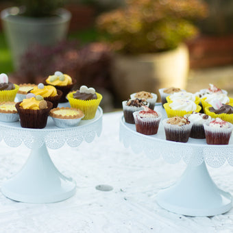 Assorted cupcakes on white cake stands outdoors