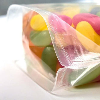 Colorful jelly beans in a clear plastic bag on a white surface